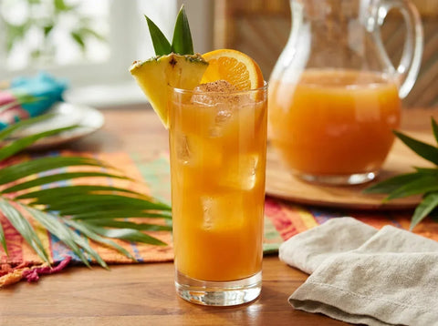 Punch planteur antillais en verre highball avec ananas, orange et muscade