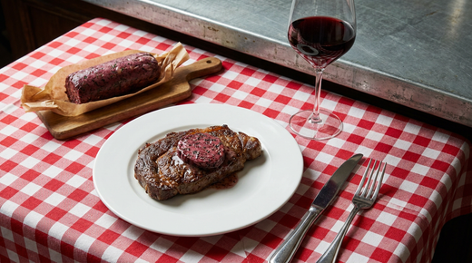 Steak grillé surmonté d'une rondelle de beurre marchand de vin, boudin de beurre sur une planche, verre de vin rouge