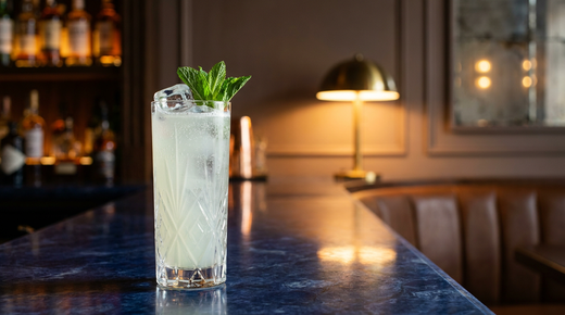 Southside Fizz vert pâle et pétillant dans un grand verre étroit, brin de menthe, comptoir de marbre bleu