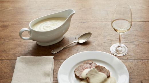 Saucière de sauce Soubise ivoire, tranches de veau rôti nappées, verre de vin blanc