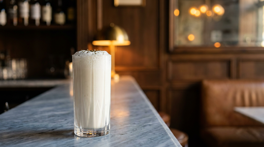 Doogh blanc opaque et pétillant avec une mousse fine, menthe séchée en surface, comptoir de marbre Bardiglio