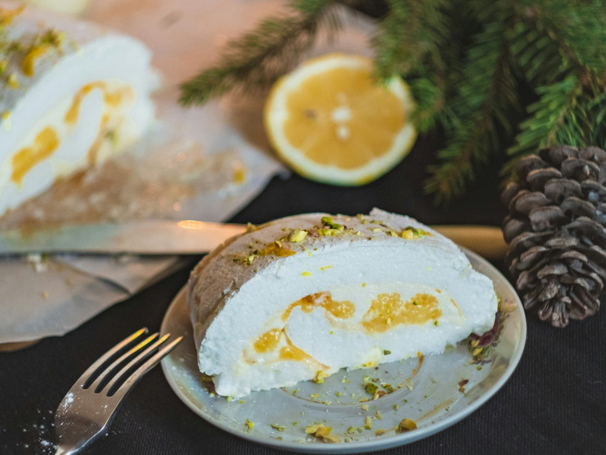 Tranche de bûche roulée meringuée au citron avec un demi-citron et des branches de sapin