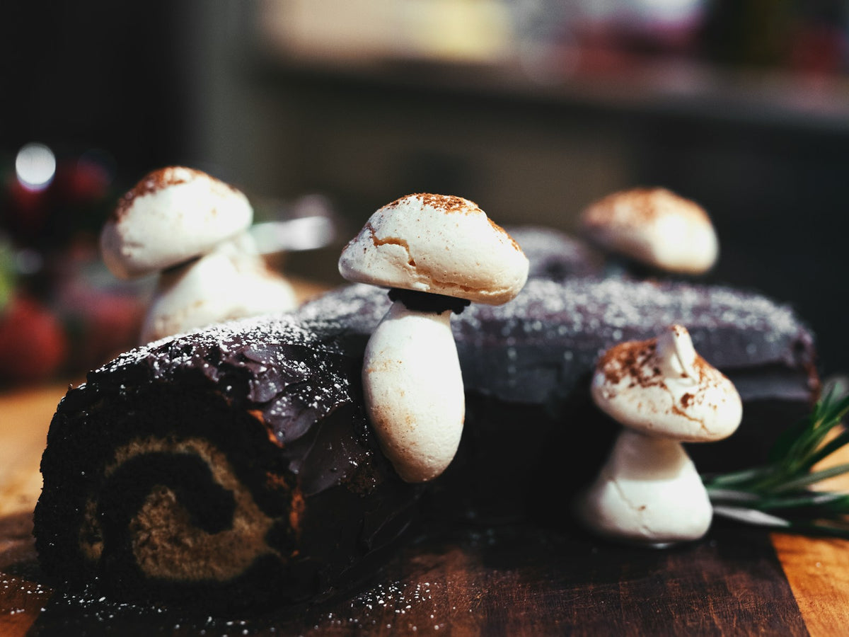 Bûche de Noël au chocolat décorée de champignons en meringue sur une planche en bois