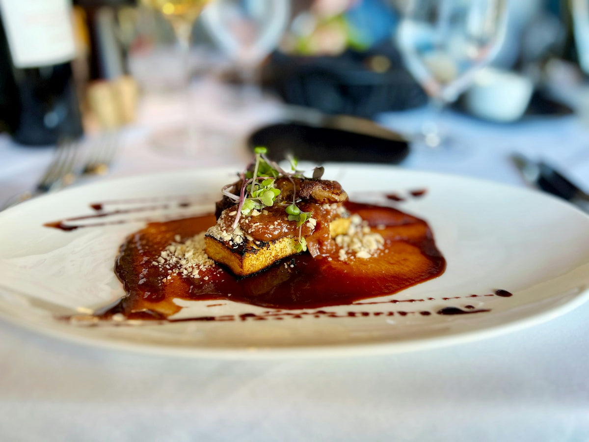 Escalope de foie gras poêlée nappée de sauce dans une assiette blanche
