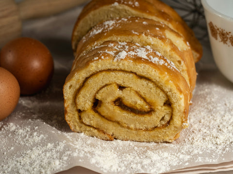 Biscuit roulé maison saupoudré de sucre, à côté d'œufs et de farine