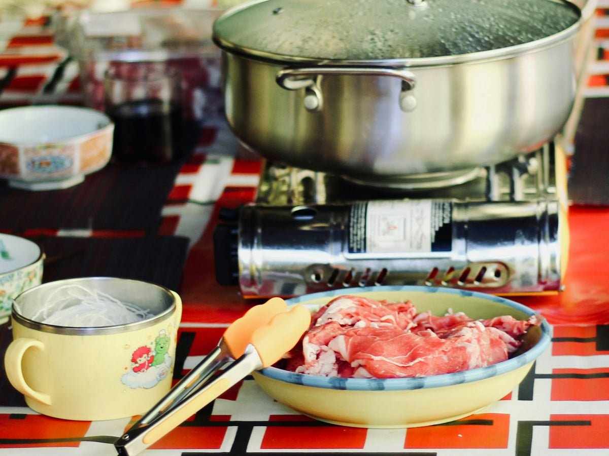 Caquelon à fondue sur réchaud avec une assiette de bœuf finement tranché
