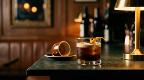 Carajillo servi sur glaçons, ligne de crème de café et zeste d'orange, sur un comptoir d'ardoise verte