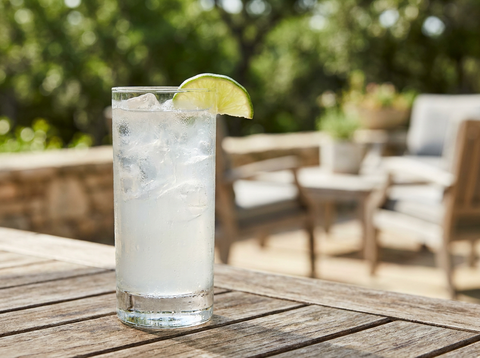 Verre highball de Ranch Water, tequila et citron vert allongés d'eau gazeuse sur glace, quartier de citron vert, lumière naturelle