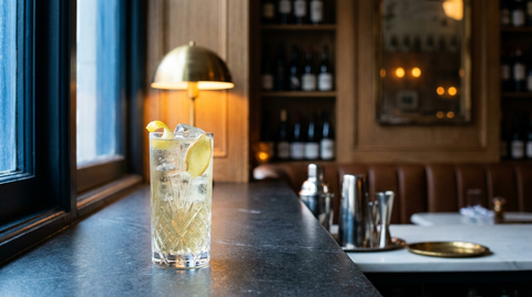 Cocktail au vin blanc et au gingembre dans un grand verre glacé, rondelle de gingembre et zeste de citron, appui de fenêtre en pierre
