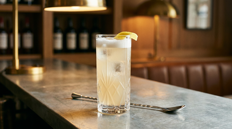 Diamond Fizz servi dans un grand verre à facettes sur un comptoir de zinc