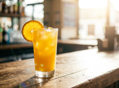 Screwdriver vodka-orange sur glaçons avec tranche d'orange dans un grand verre, comptoir de bar lumineux