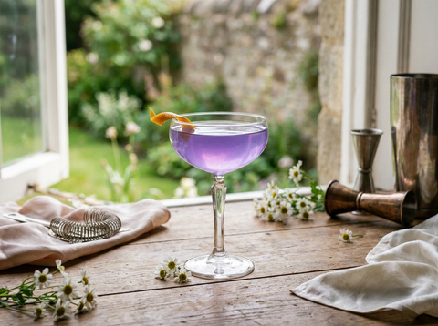 Cocktail Water Lily violet lumineux dans une coupe, zeste d'orange