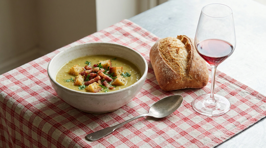 Soupe de pois cassés aux croûtons et lardons, nappe à carreaux, pain, verre de vin rouge