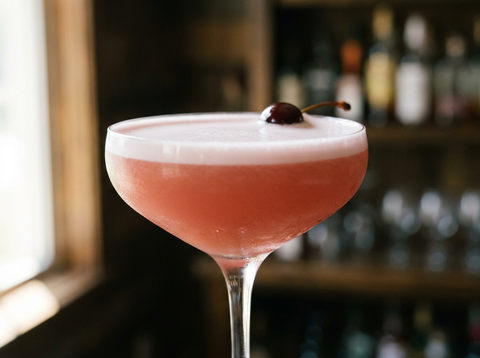 Pink Lady, cocktail rose au gin et blanc d'œuf servi en verre à cocktail avec une cerise