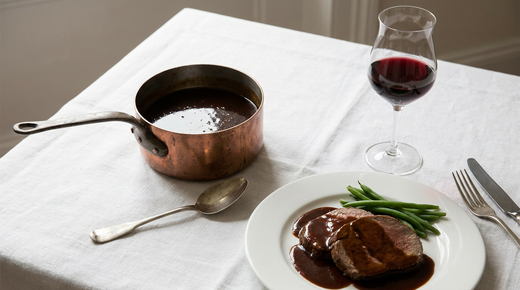 Sauce au madère brune et brillante en casserole de cuivre, rôti de veau nappé, verre de vin rouge