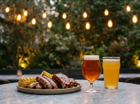Terrasse de brasserie chic au crépuscule : saucisses, travers laqués et maïs grillés, avec une ale ambrée cuivrée et une pale ale dorée.
