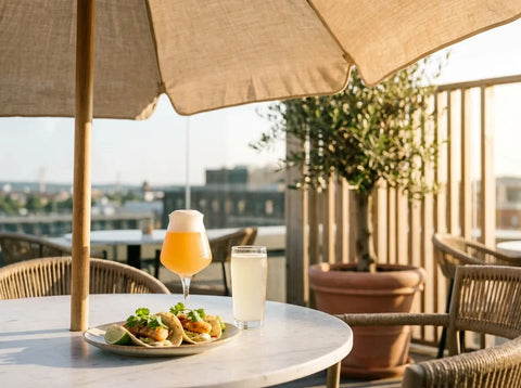 Terrasse de brasserie en plein été : tacos de poisson au citron vert, une NEIPA trouble orangée et une gose pâle couvertes de buée.