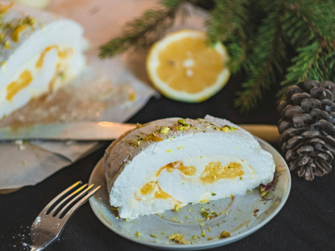 Tranche de bûche roulée meringuée au citron avec un demi-citron et des branches de sapin