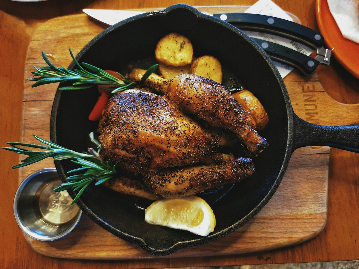 Volaille rôtie et farcie dans une poêle en fonte avec pommes de terre et romarin