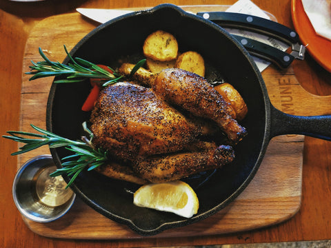Volaille rôtie et farcie dans une poêle en fonte avec pommes de terre et romarin