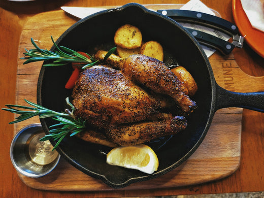 Volaille rôtie et farcie dans une poêle en fonte avec pommes de terre et romarin