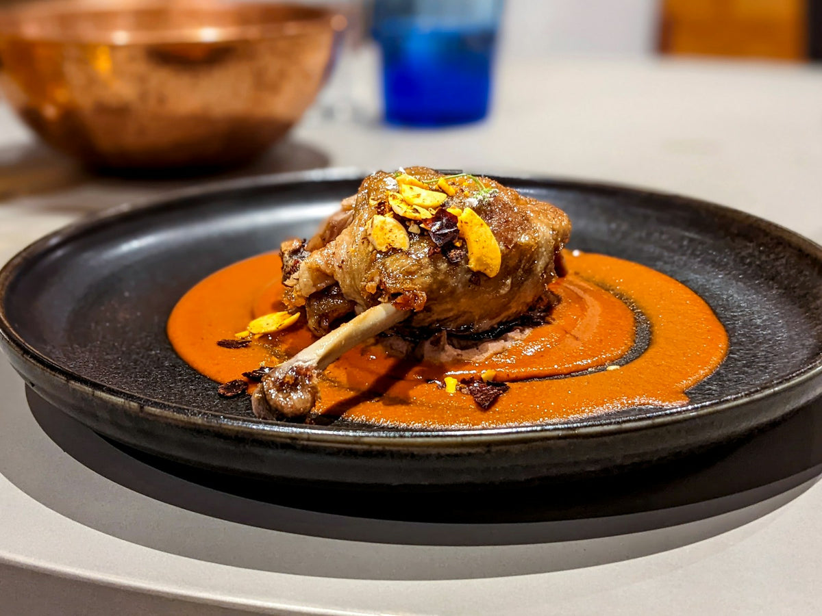 Cuisse de canard confite dorée dressée sur une assiette noire