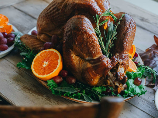Volaille rôtie dorée sur un plat de fête avec oranges et herbes