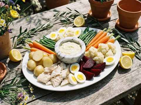Grand aïoli provençal sur un plat de service : morue effeuillée, pommes de terre, carottes, haricots verts, chou-fleur, œufs durs et sauce à l'ail au mortier