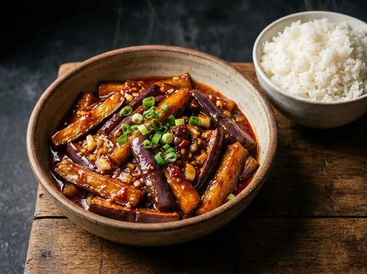 Aubergines sichuanaises yuxiang au wok : bâtonnets d’aubergine fondants dans une sauce brune brillante à l’ail, gingembre et piment, parsemés d’oignon vert