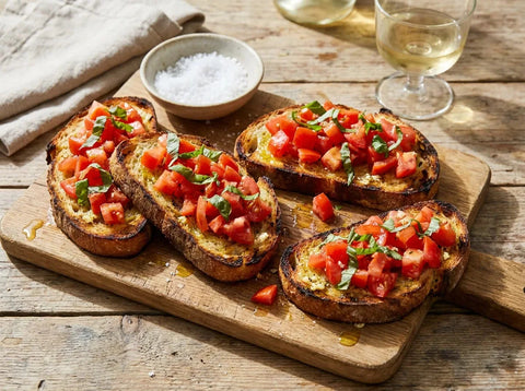 Bruschette italiennes sur planche : pain de campagne grillé frotté à l’ail, dés de tomates mûres, basilic frais et filet d’huile d’olive