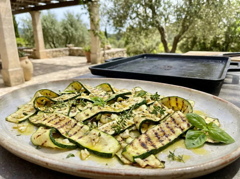 Tranches de courgettes grillées à la plancha, dorées et marquées, avec ail, herbes fraîches et huile d’olive