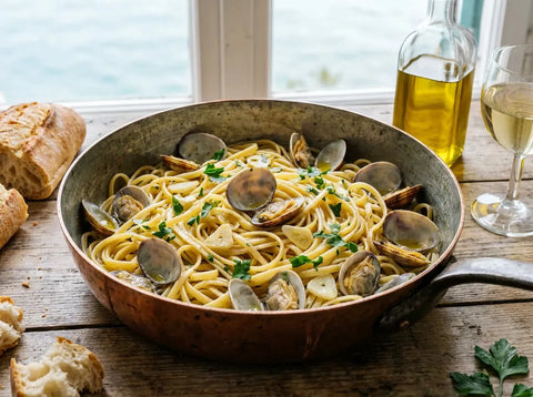 Linguine aux palourdes alle vongole dans une poêle : pâtes enrobées de jus iodé, palourdes ouvertes en coquille, ail et persil