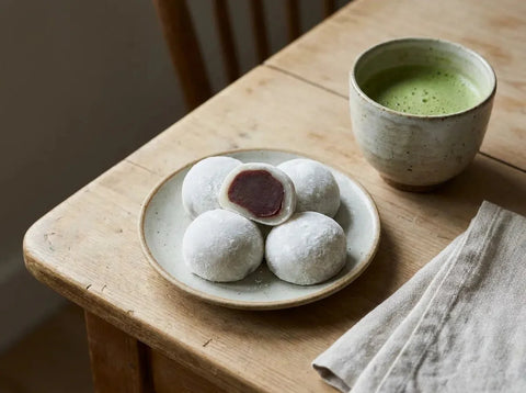 Mochis japonais moelleux roulés dans la fécule, l’un coupé montrant le cœur de pâte de haricot rouge
