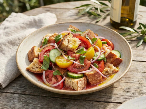 Panzanella toscane : salade de pain de campagne rassis, tomates mûres, concombre, oignon rouge et basilic à l’huile d’olive dans un grand saladier