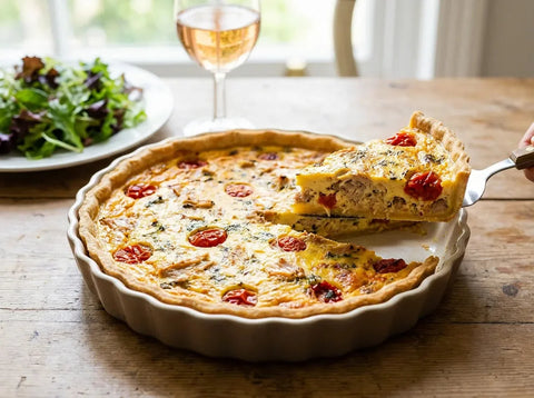 Quiche au thon et tomates dorée, une part coupée montrant l’appareil crémeux, le thon émietté et les rondelles de tomate
