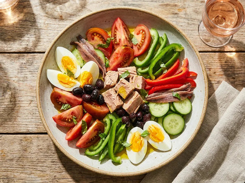 Salade niçoise traditionnelle : tomates, œufs durs, thon, anchois, olives de Nice, poivron et concombre dressés côte à côte
