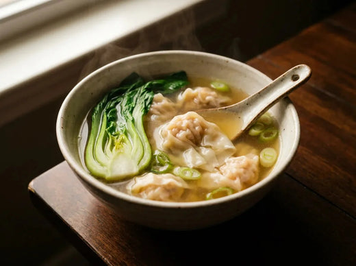 Bol de soupe won ton : raviolis translucides au porc et à la crevette dans un bouillon clair, avec brèdes vertes et oignons nouveaux