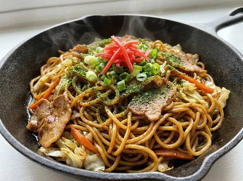 Yakisoba : nouilles sautées japonaises avec porc, chou et carotte, laquées d’une sauce brune, parsemées de ciboule