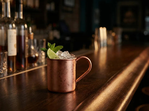 London Mule dans une mug en cuivre givée avec glace pilée, citron vert et menthe sur un comptoir de bar