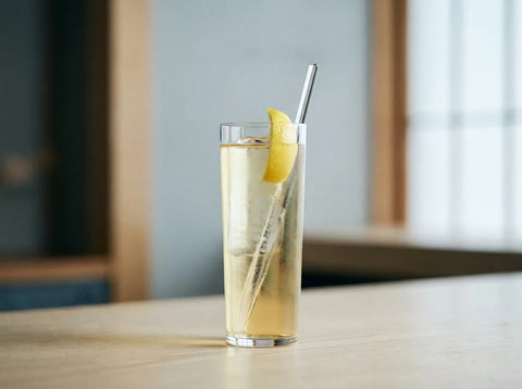 Highball japonais, whisky et eau gazeuse sur gros glaçons dans un grand verre droit avec zeste de citron
