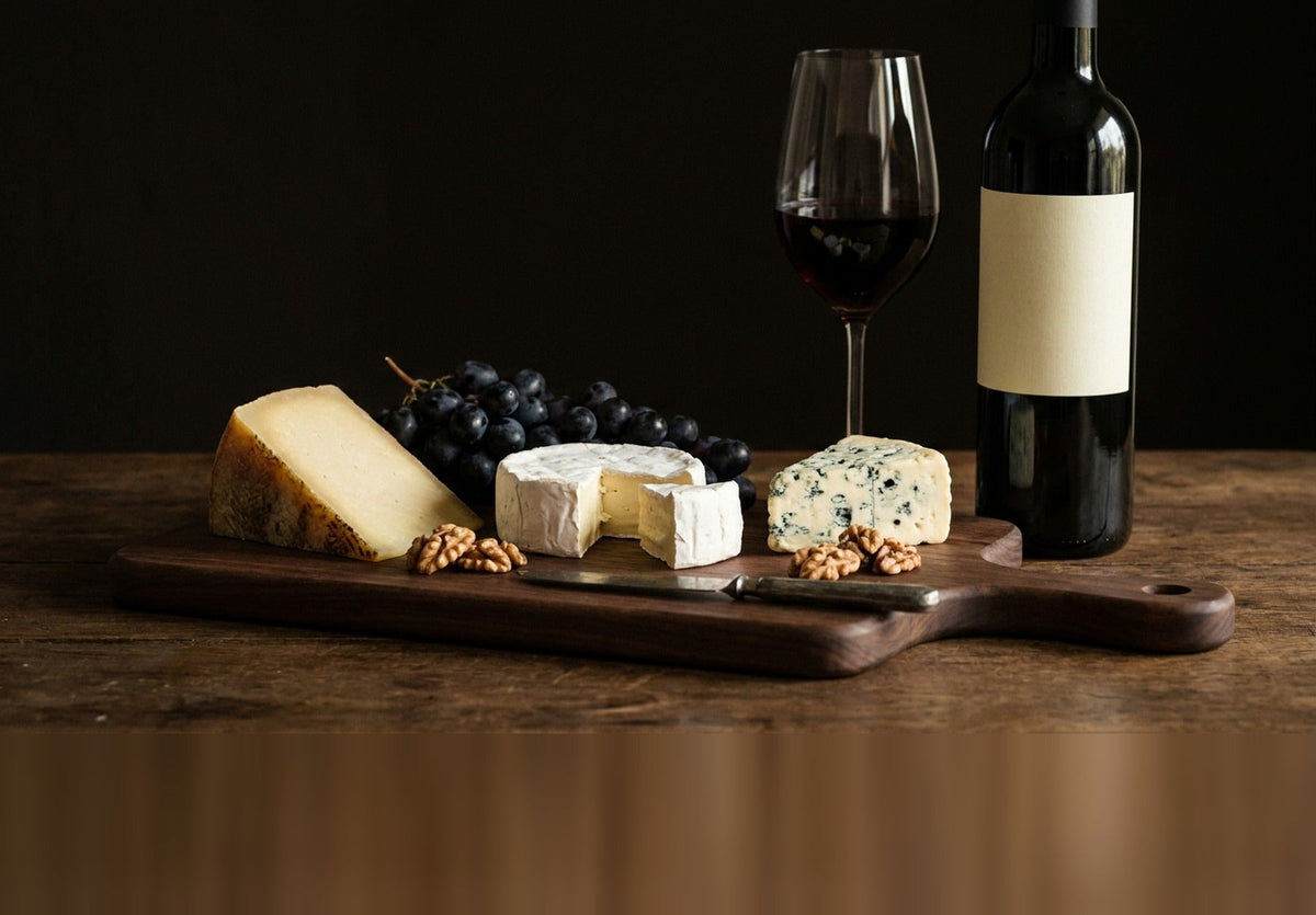 Plateau de fromages affinés sur une planche de noyer, verre et bouteille de vin rouge