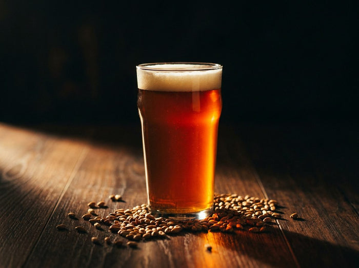 Verre de bière ambrée cuivrée et malts caramel